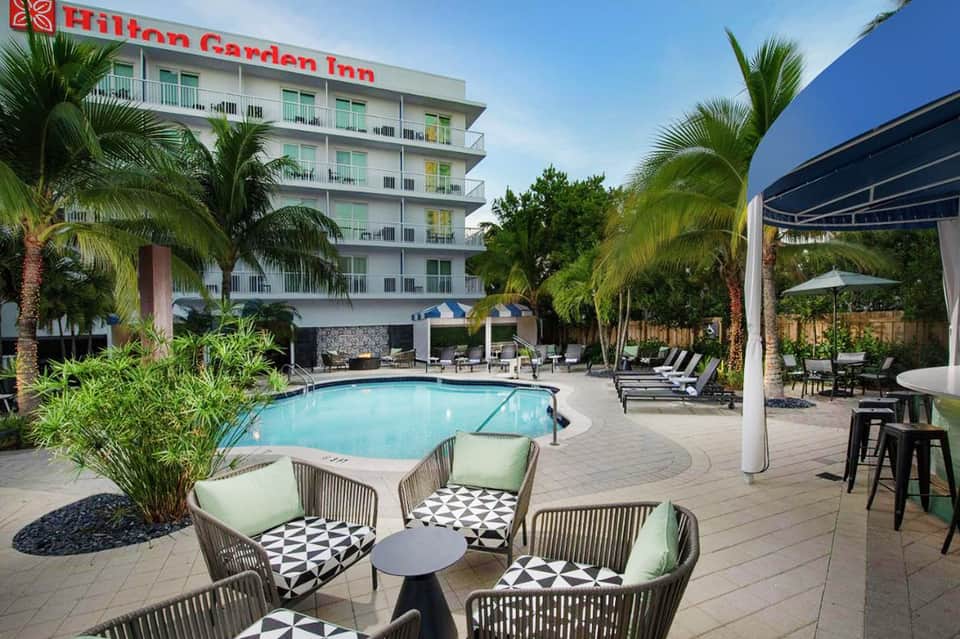 Hilton Garden Inn courtyard pool with palm trees and modern lounge seating