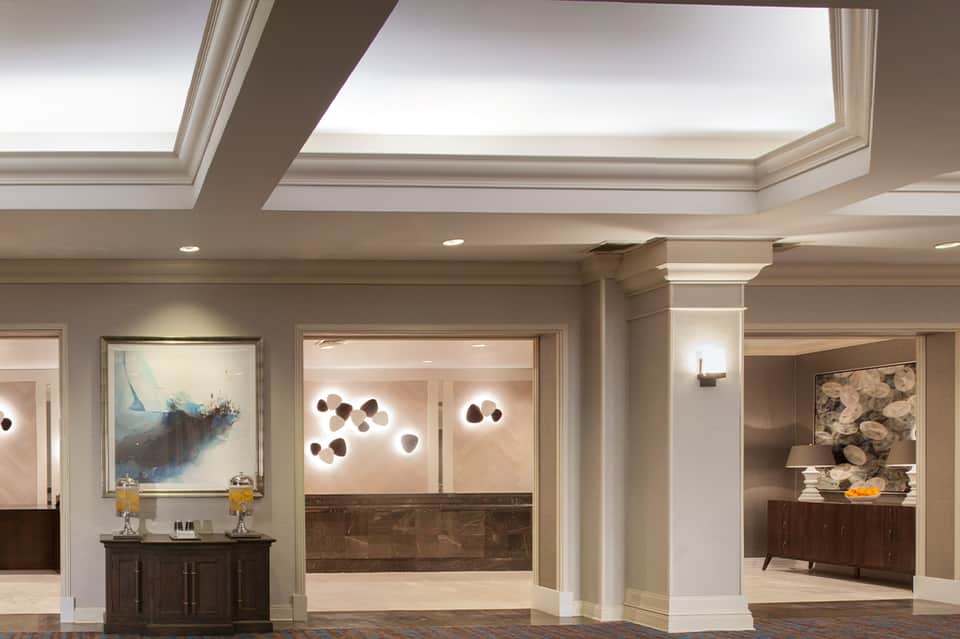 Elegant hotel corridor with skylights, marble accents, artistic wall fixtures, and modern decor