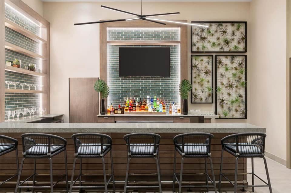 Contemporary bar with geometric ceiling fan, green tile backsplash, and tropical wall art