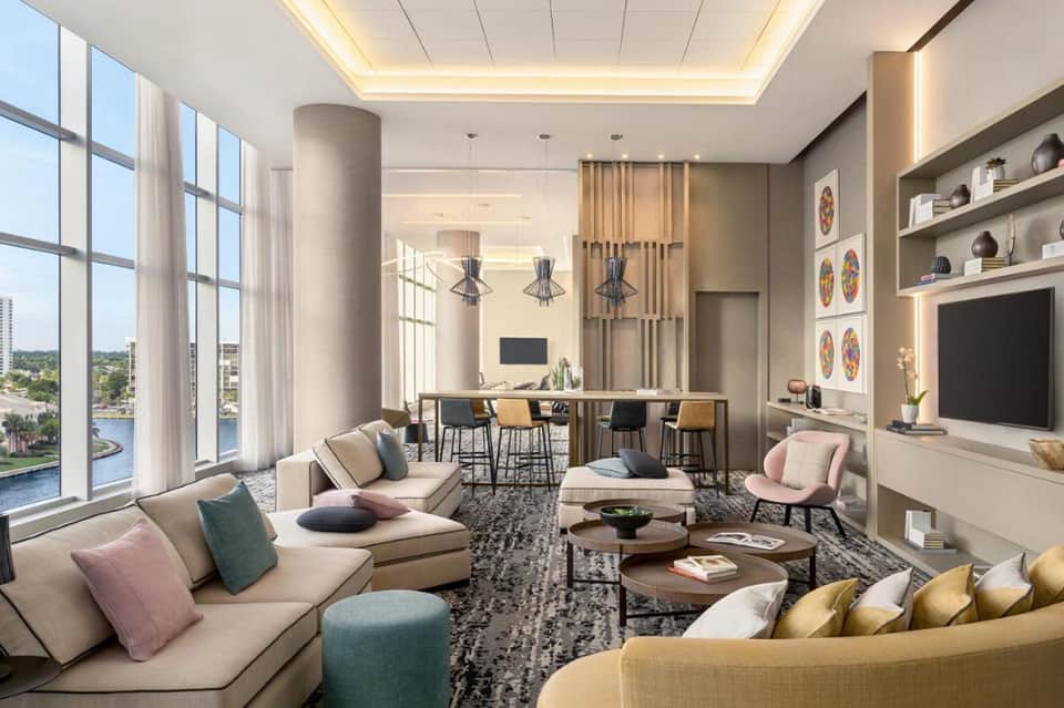 Modern hotel suite living room with couches, waterfront views, pendant lights, and entertainment area