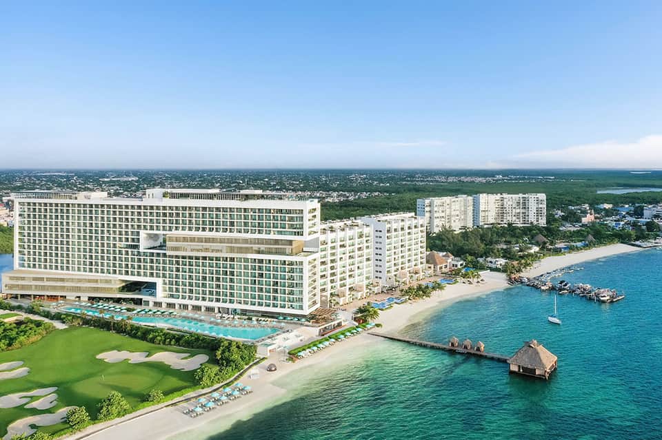 Beachfront resort with large pool, golf course, and turquoise ocean view