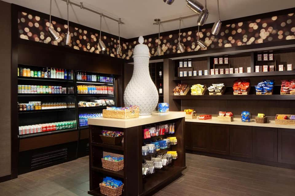 Modern hotel convenience store with refrigerated beverages, snacks, and decorative lighting