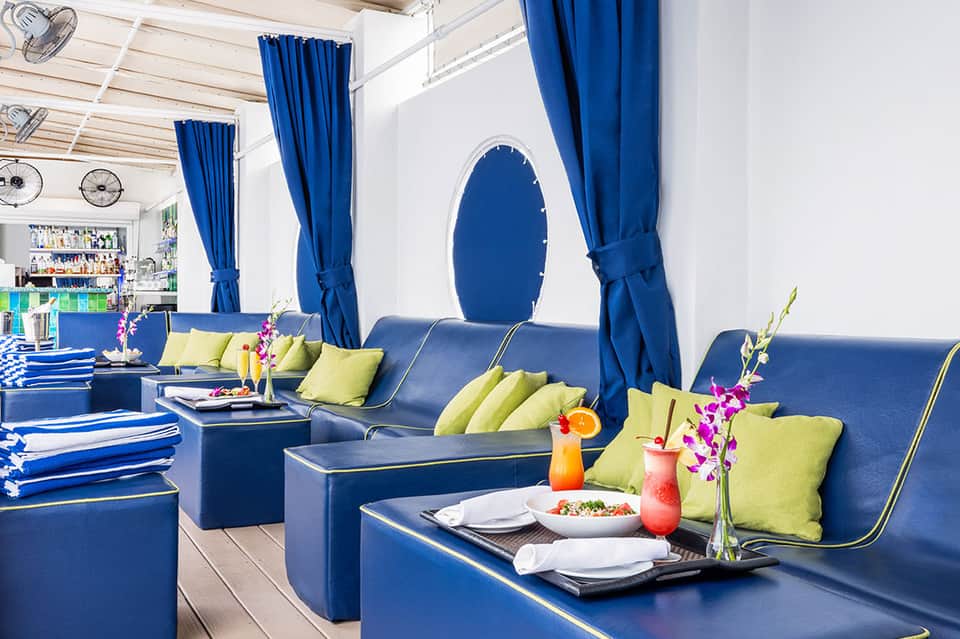 Blue and yellow lounge bar with plush seating, flowered centerpieces, and arched window