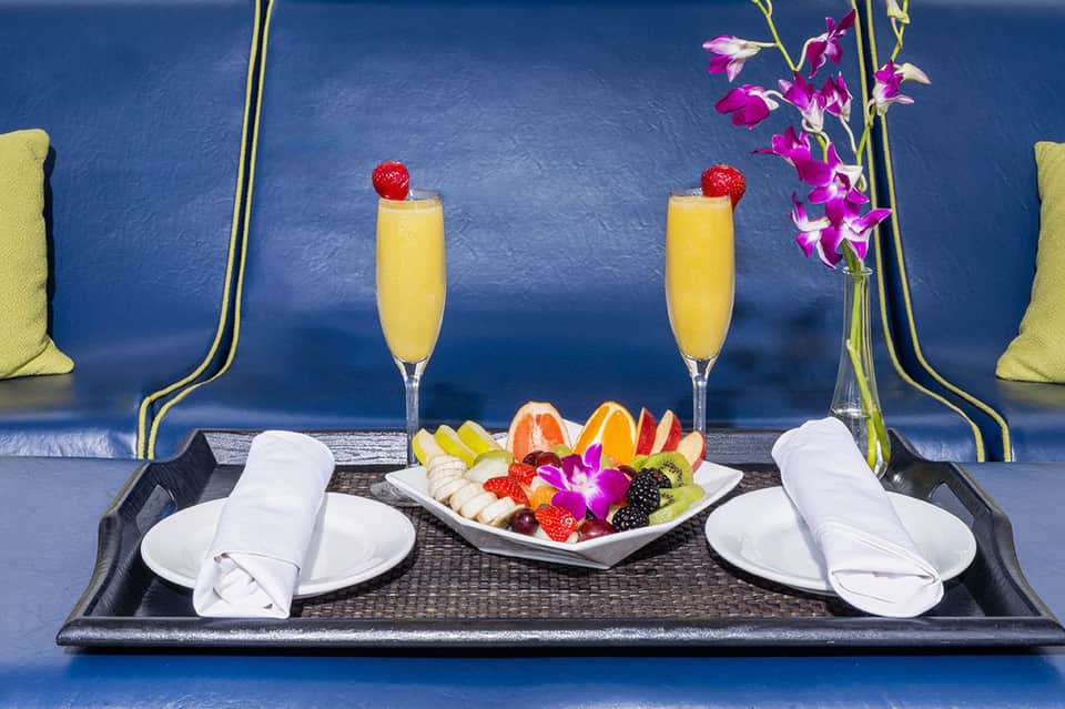 Elegant in-room dining setup with champagne, fresh fruit platter, and blue accent wall