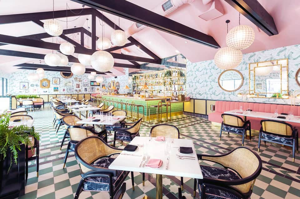 Colorful modern restaurant interior with pink ceiling, checkered floor, and hanging globe lights