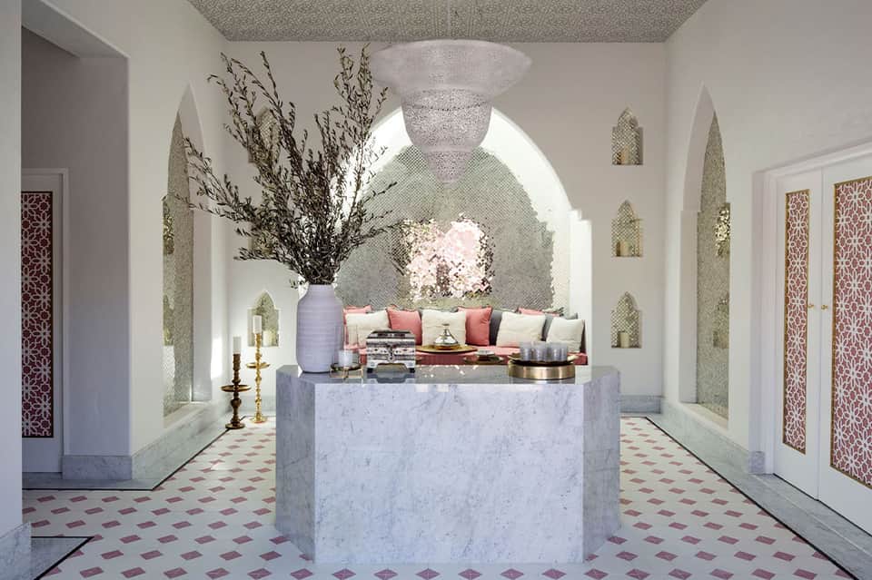 Elegant marble spa entrance with arched alcoves, flowers, and decorative geometric flooring