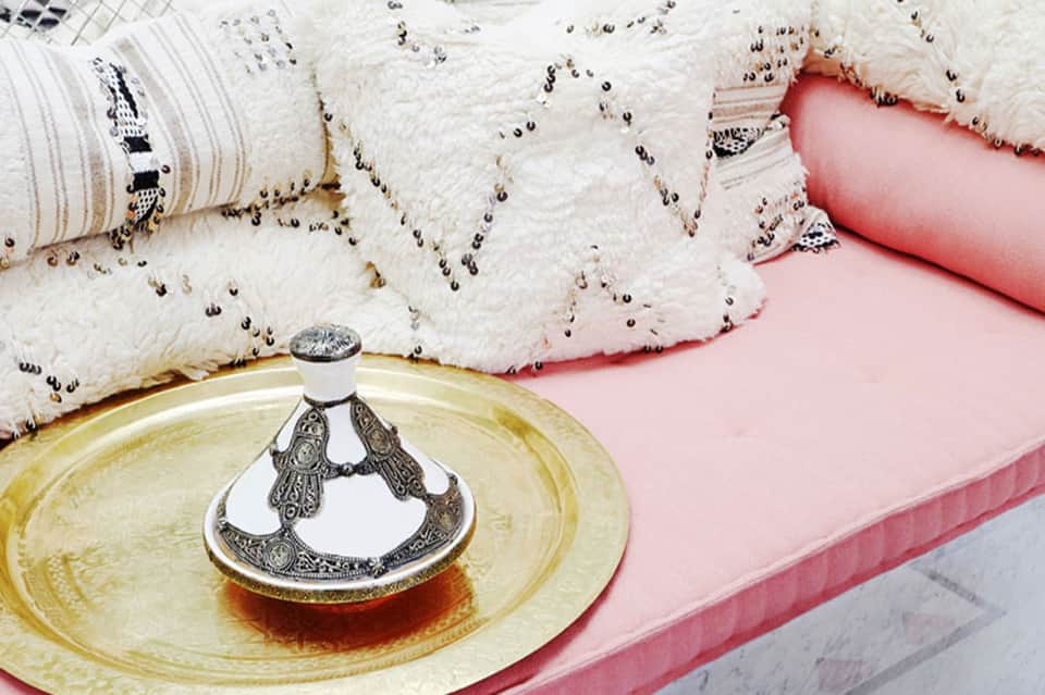 Luxury bed with ornate white pillows, pink bedding, and decorative gold bowl on nightstand