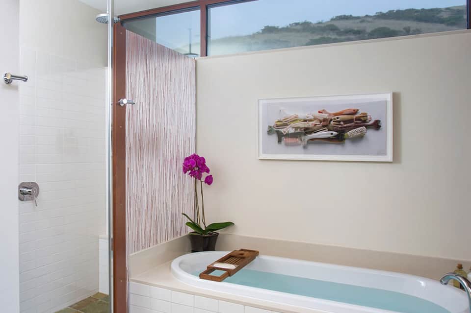 Luxury bathroom with soaking tub, rainfall shower, and scenic hillside window view
