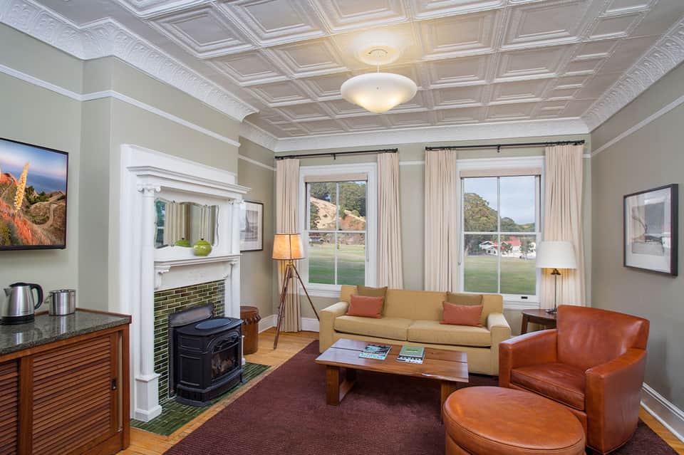 Elegant hotel suite living room with fireplace, coffered ceiling, sofa, and large windows