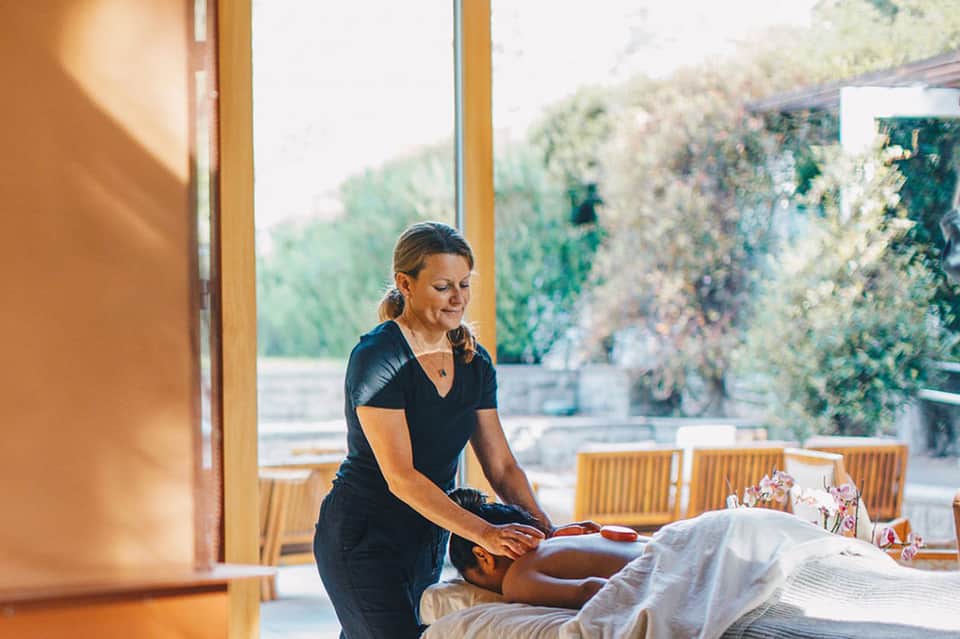 Spa therapist performing massage treatment on client with mountain view