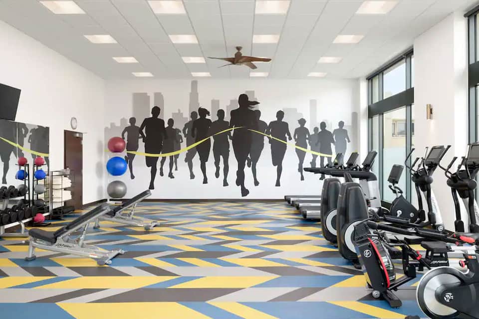 Modern fitness center with exercise bikes, weights, and motivational mural of running athletes
