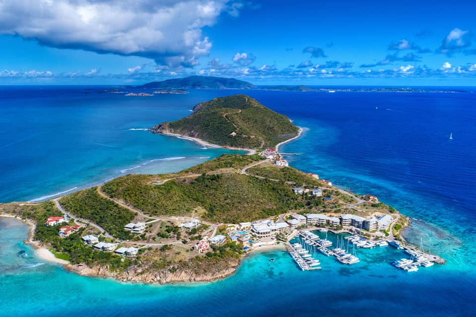 Aerial view of tropical island resort with marina, pristine beaches, and surrounding islands