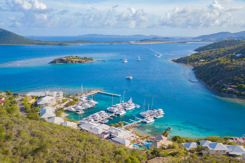 Aerial marina view with sailboats docked in turquoise bay surrounded by tropical vegetation