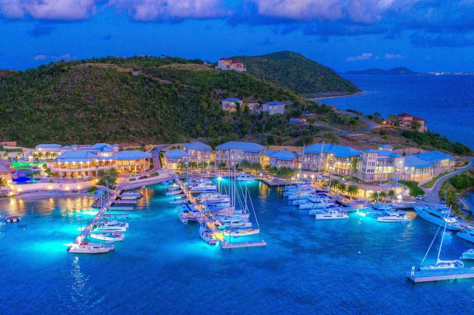 Illuminated waterfront resort village nestled on hillside overlooking harbor at dusk
