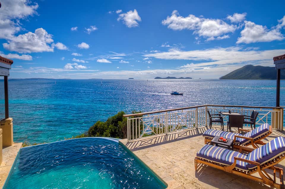 Private infinity pool on oceanfront terrace with striped lounge chairs and panoramic tropical water views