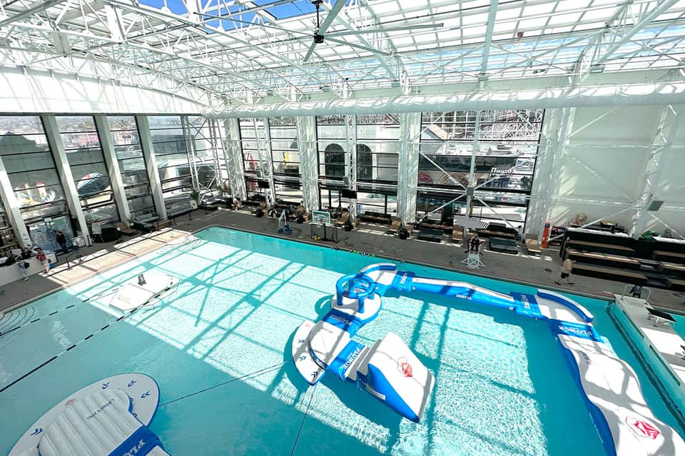 Indoor aquatic center with turquoise pool and water sports equipment under glass ceiling