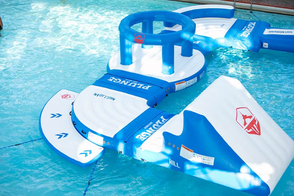 Swimming pool with inflatable water toys and floats in bright blue and white colors