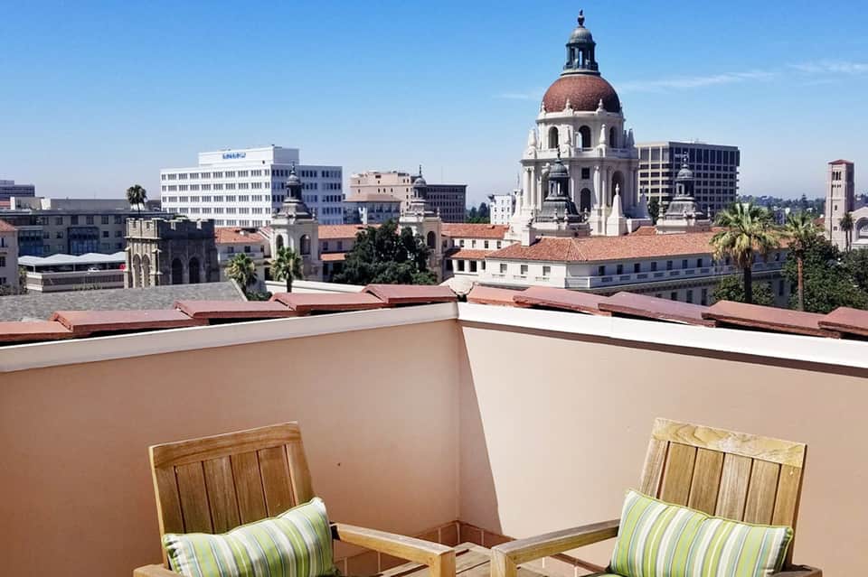 Rooftop terrace with striped lounge chairs overlooking historic downtown cityscape and domed cathedral