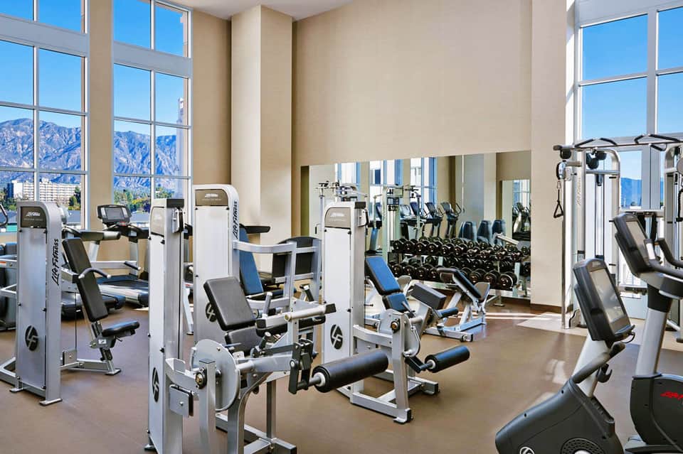 Modern fitness center with cardio equipment, weights, mirrors, and mountain views through large windows
