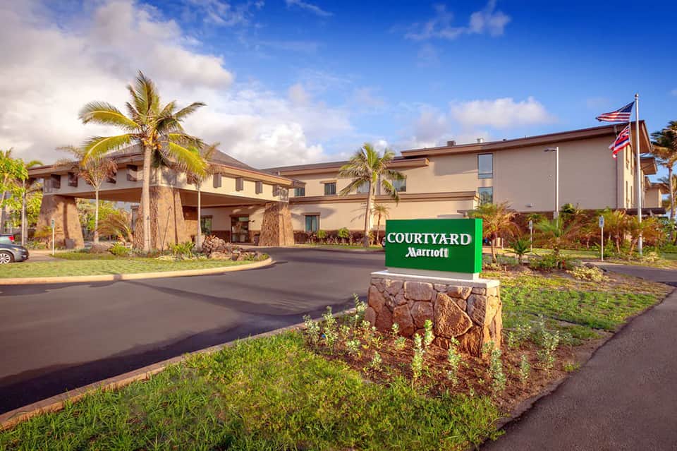 Courtyard Marriott entrance with palm trees, manicured lawn, and tropical landscaping