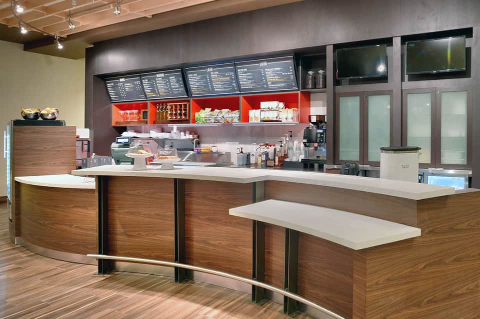 Contemporary hotel café counter with red accents, menu boards, and modern fixtures