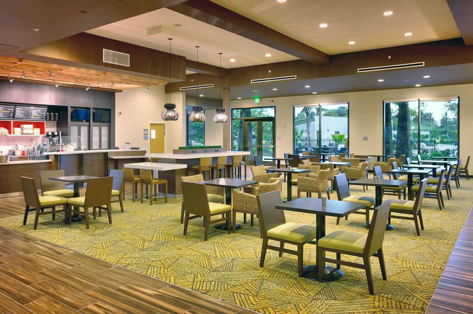 Casual dining area with yellow seating, pendant lights, and large windows overlooking grounds