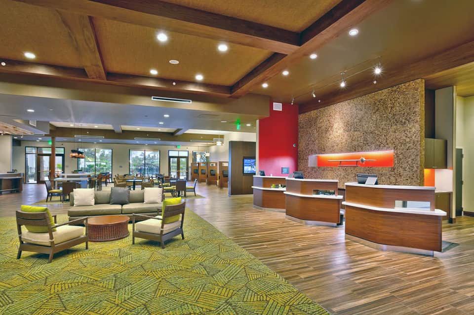 Hotel lobby with modern furnishings, wooden accents, geometric carpet, and warm lighting