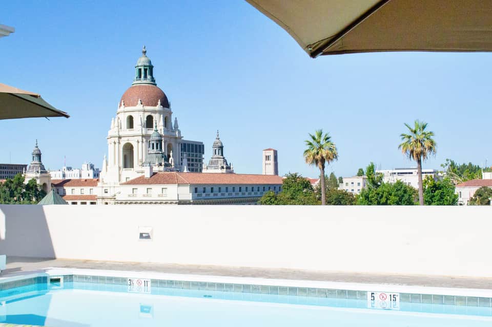 Rooftop pool with city skyline view featuring historic dome building and palm trees
