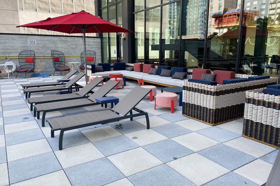 Urban rooftop lounge with black loungers, red umbrella, and city skyline views