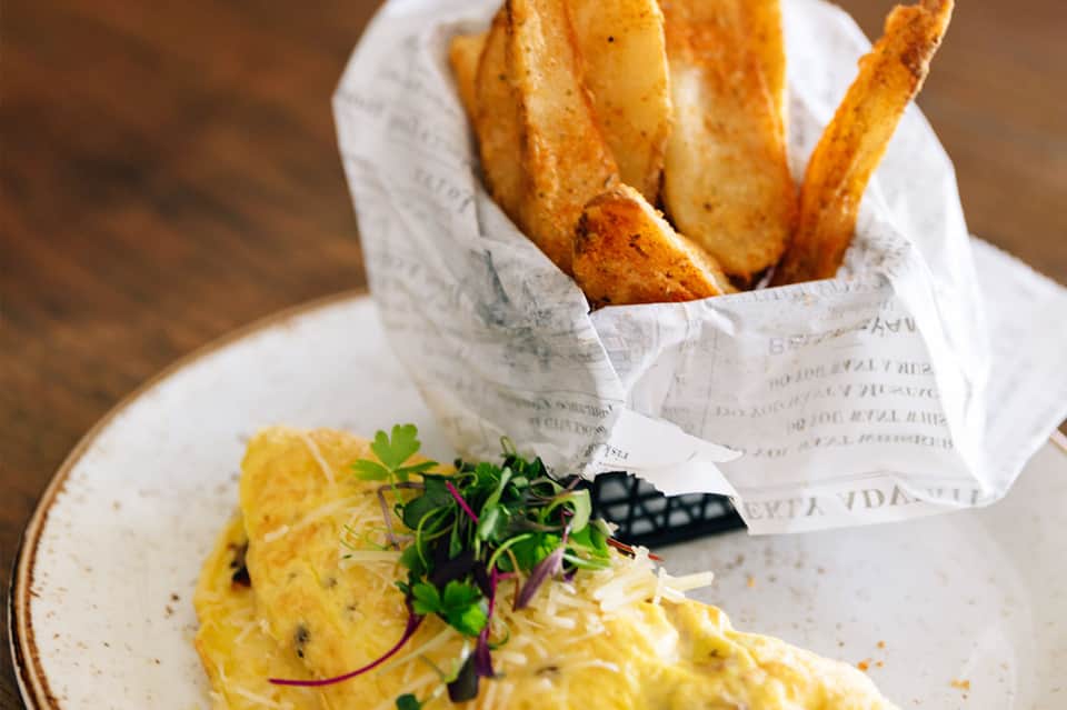 Gourmet plated dish with golden fries and microgreens beside fresh seafood preparation