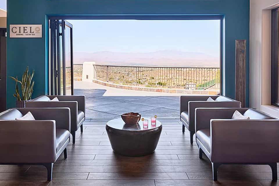 Modern spa lounge with teal walls, contemporary seating, and panoramic desert landscape views