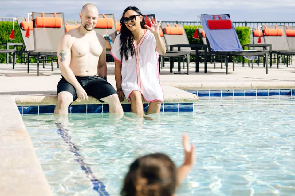 Man and woman relaxing poolside at resort with colorful lounge chairs behind