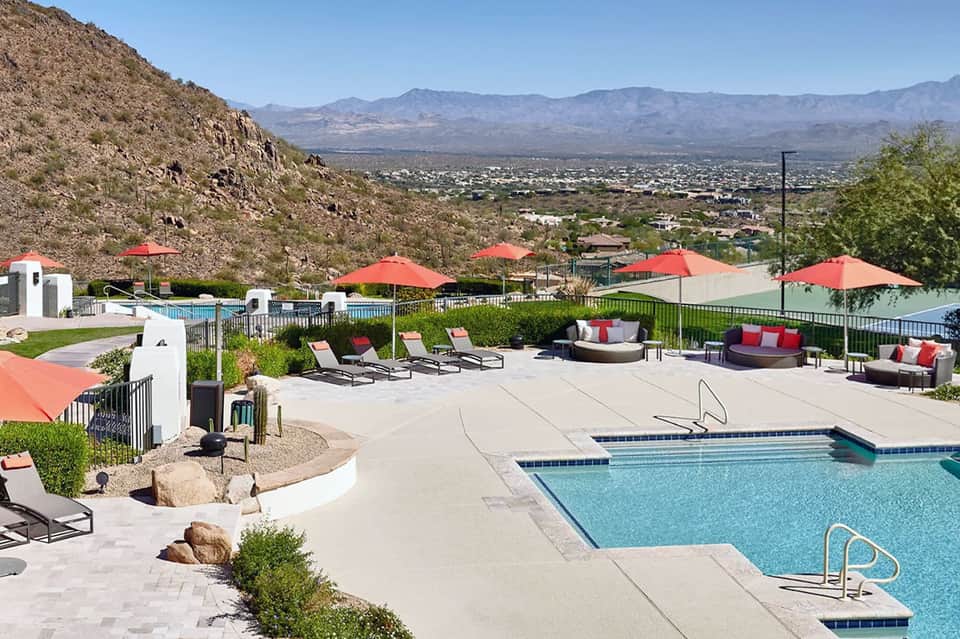 Desert resort pool with red umbrellas, mountain views, and modern spa facilities