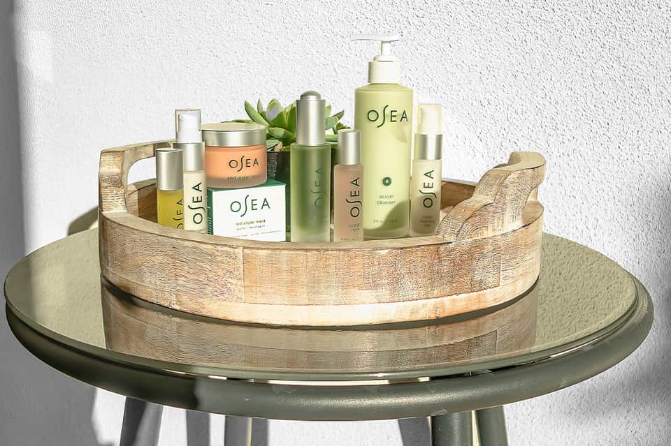 Display of OSEA skincare and wellness products arranged on wooden tray