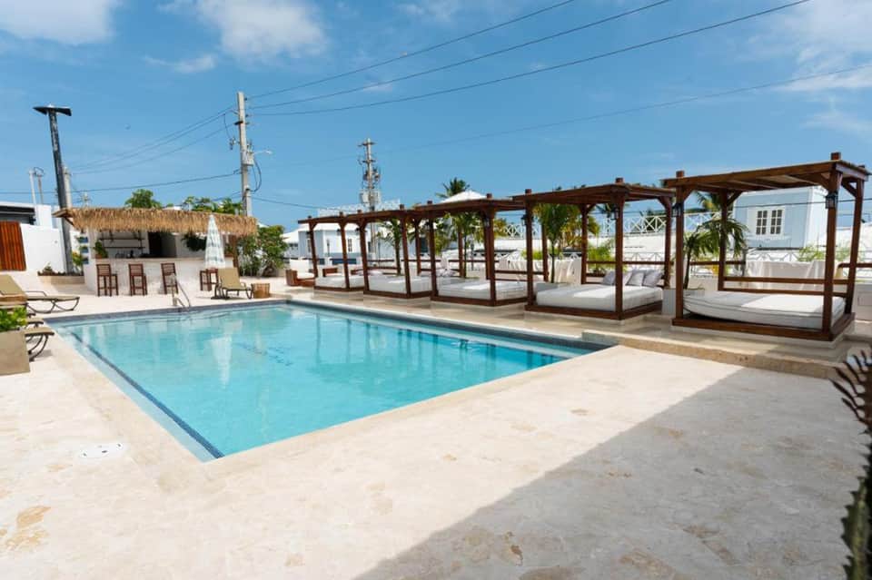 Resort pool with wooden pergola structures and lounge cabanas in tropical setting