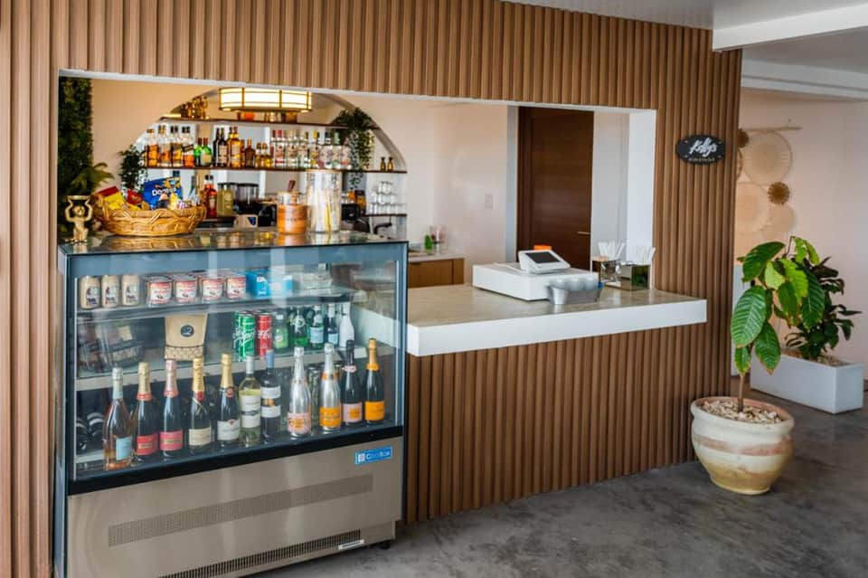 Resort bar and reception counter with wood paneling, beverage display, and tropical decor