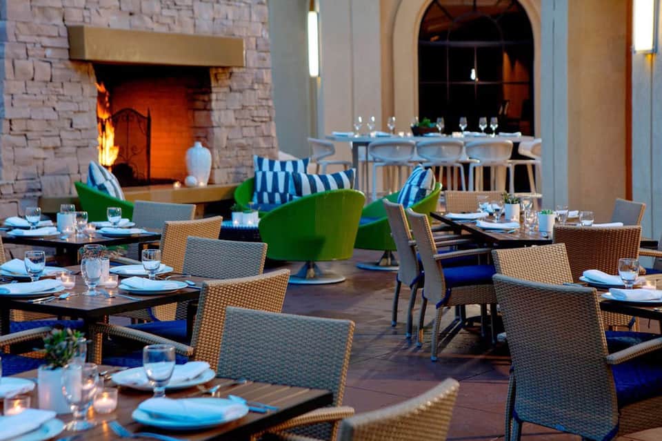 Resort dining area with fireplace, green accents, and formal table settings