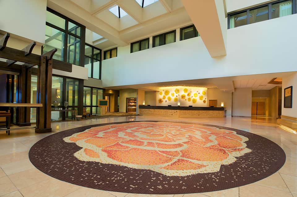 Spacious hotel lobby with soaring ceiling, architectural skylight, decorative circular floor pattern, and reception desk