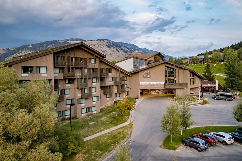 Snow King Hotel mountain lodge with timber architecture, mountains, trees, and parking area