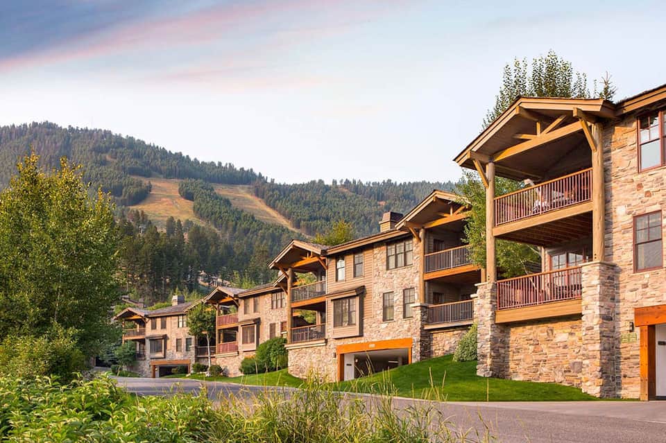 Luxury mountain resort chalets with stone architecture, decks, and forested hillside setting