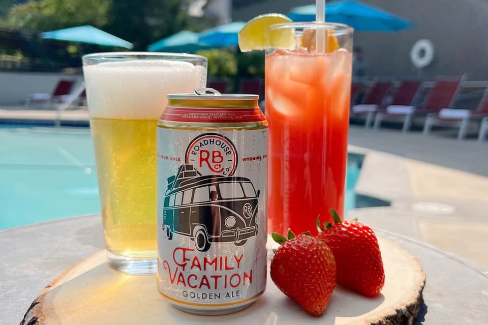Poolside beverages including beer, cocktails, and fresh strawberries on wooden tray