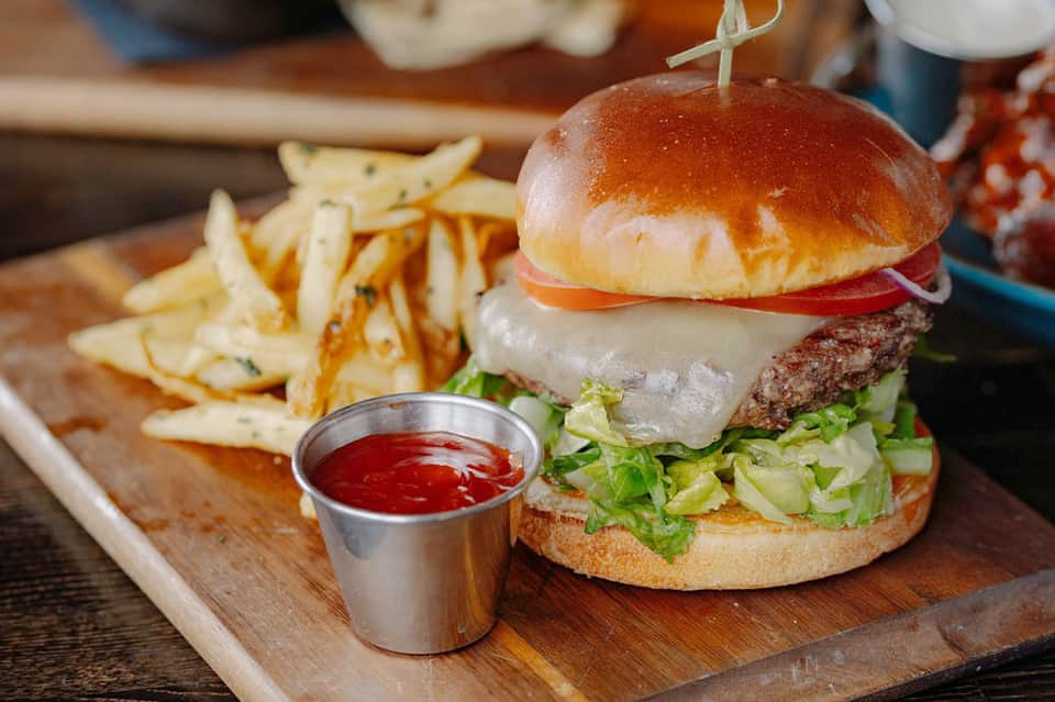 Gourmet cheeseburger with fries and ketchup on wooden serving board