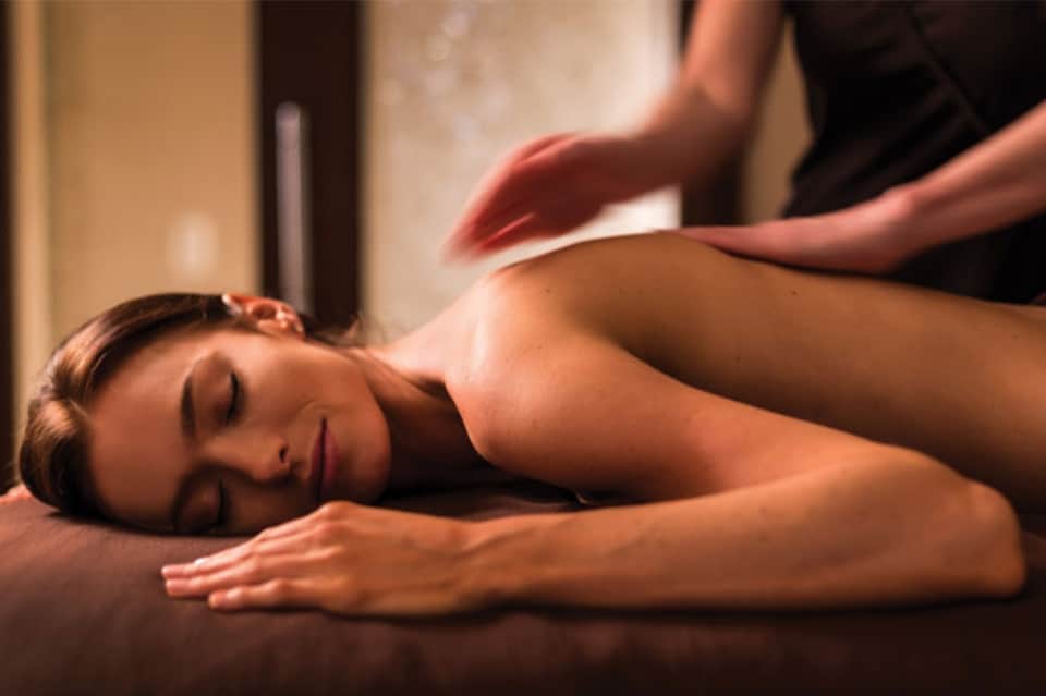 Woman receiving relaxing spa massage treatment on table in warm-lit spa setting