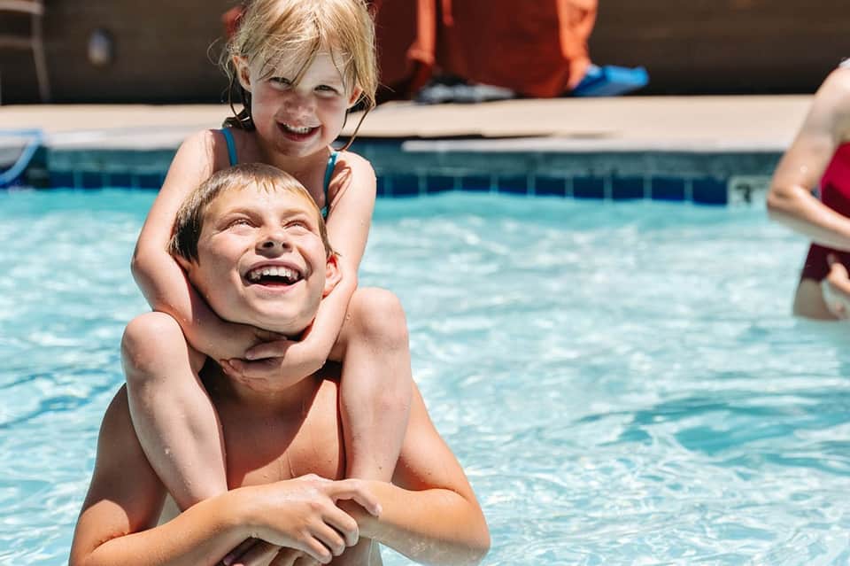 Two young children playing happily in resort swimming pool during daytime