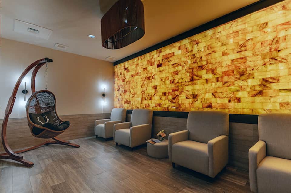 Wellness lounge with hanging chair, comfortable seating, and cork accent wall