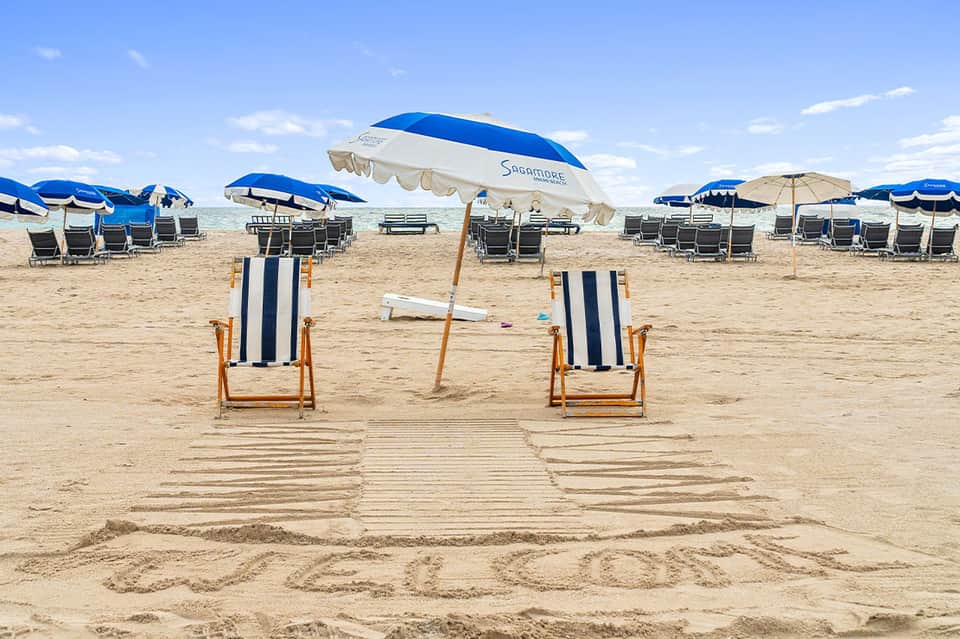 Beach chairs and umbrellas on sandy beach with striped loungers and blue parasols