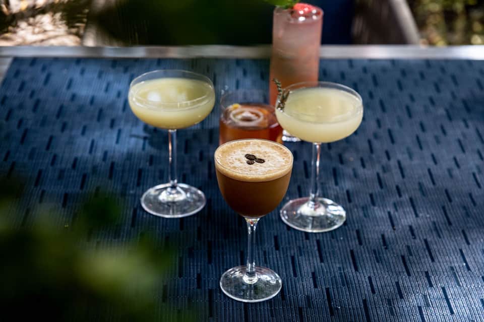 Cocktails served poolside on blue textured table with tropical drinks