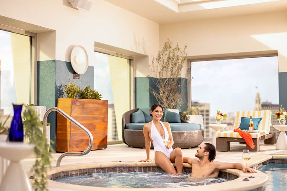 Couple enjoying indoor spa tub with panoramic city views and modern décor