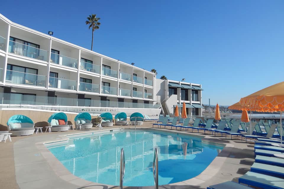 Contemporary hotel pool with turquoise water, modern buildings, and cabana seating