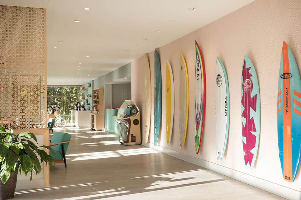 Bright hotel corridor with surfboard wall display, wooden ceiling details, and coastal decor accents